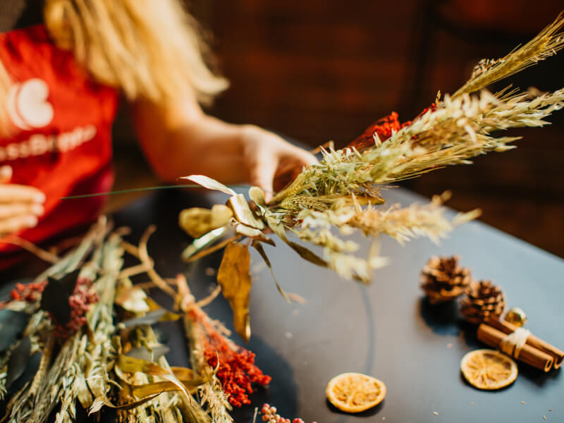 Dried flowers in focus, woman behind arranging them